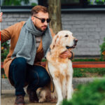 Una persona con bastone bianco accanto a un cane guida